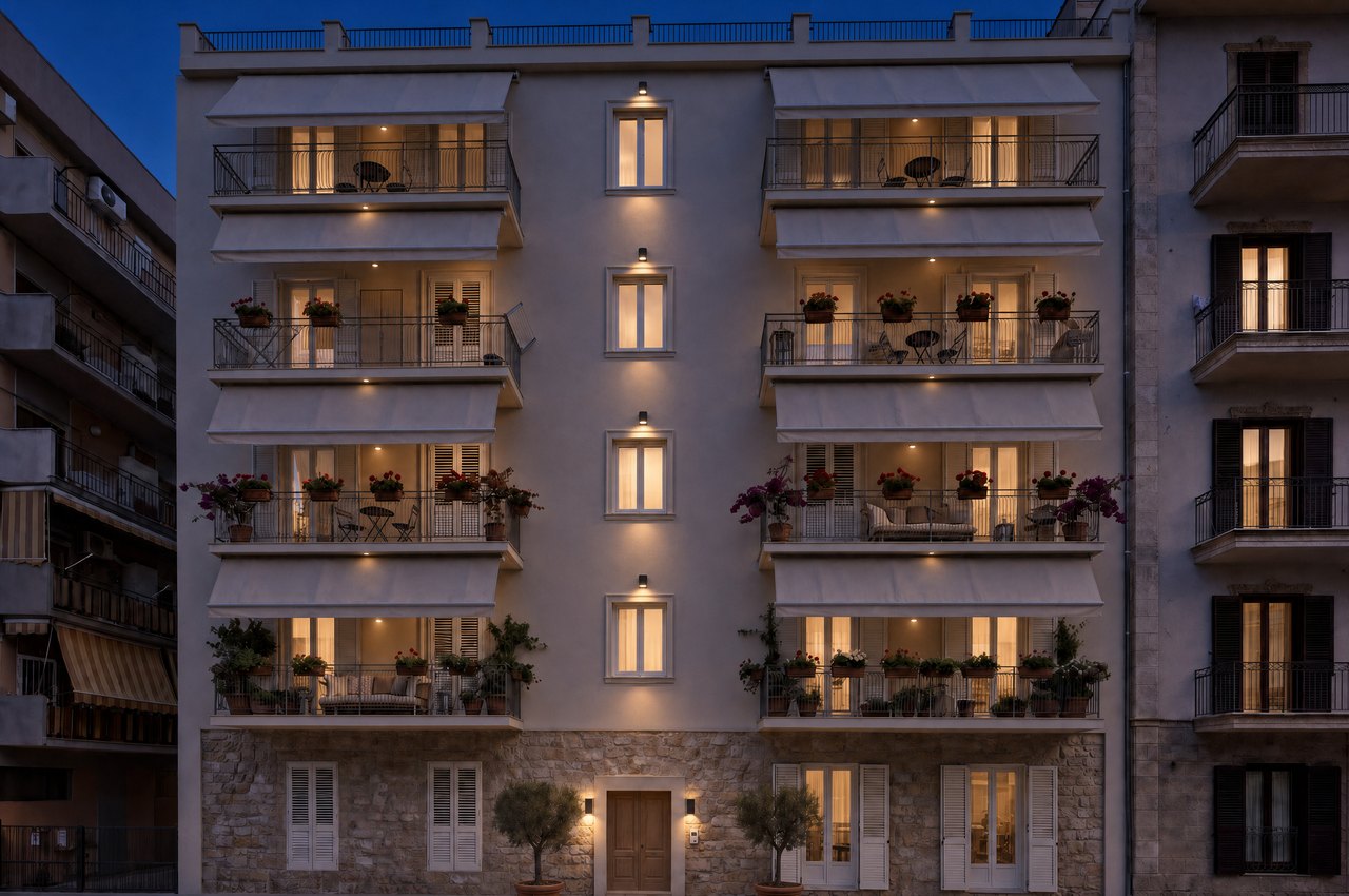 Render di progetto della facciata di via Abramo Lincoln 35 all’ora blu: faretti della scala e del portone accesi, balconi illuminati sotto le tende.